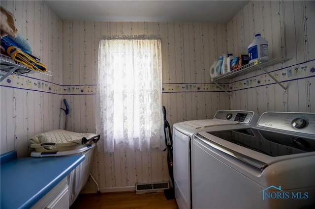 laundry room with wallpapered walls, washing machine and dryer, laundry area, and visible vents