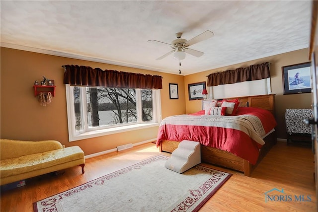 bedroom with baseboards, visible vents, wood finished floors, and ceiling fan
