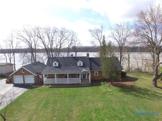 view of front of home featuring driveway, a front yard, covered porch, and a chimney