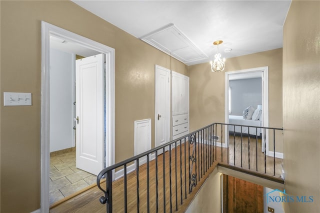 corridor featuring an upstairs landing, baseboards, and attic access