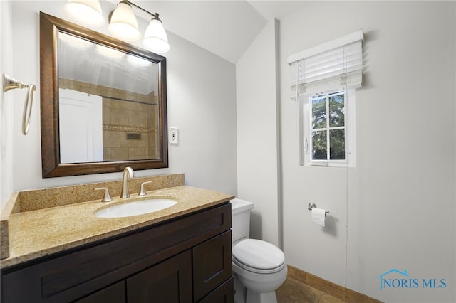 bathroom featuring toilet, vanity, tile patterned flooring, and vaulted ceiling