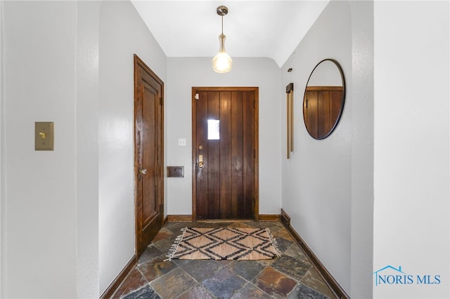 doorway featuring baseboards and stone tile floors