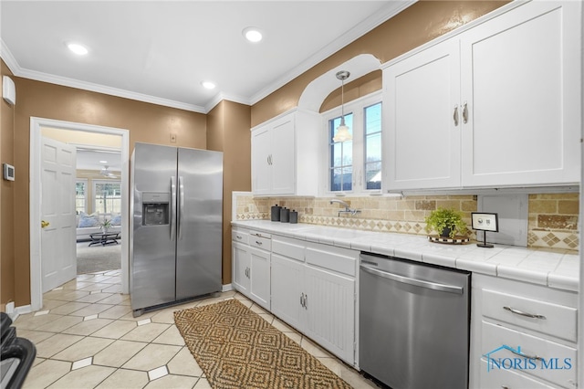 kitchen with white cabinets, tile counters, stainless steel appliances, and decorative backsplash