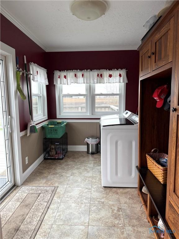 clothes washing area featuring ornamental molding, baseboards, washer and dryer, and a textured ceiling