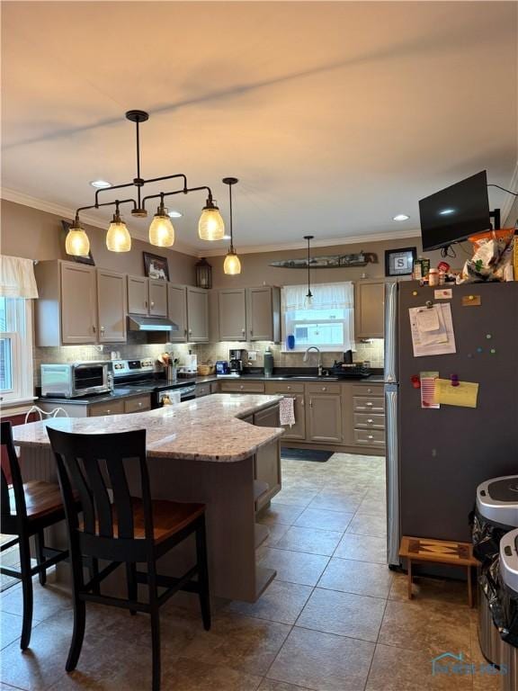 kitchen with stainless steel appliances, tasteful backsplash, under cabinet range hood, gray cabinets, and a center island