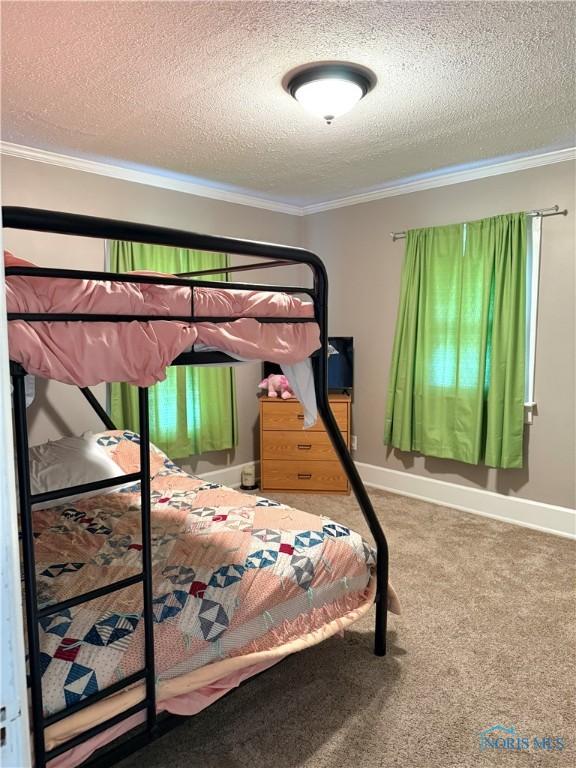 bedroom with baseboards, carpet floors, ornamental molding, and a textured ceiling