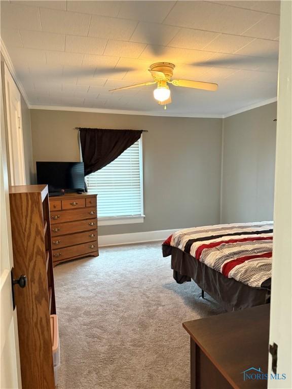 bedroom featuring carpet floors, ornamental molding, baseboards, and ceiling fan