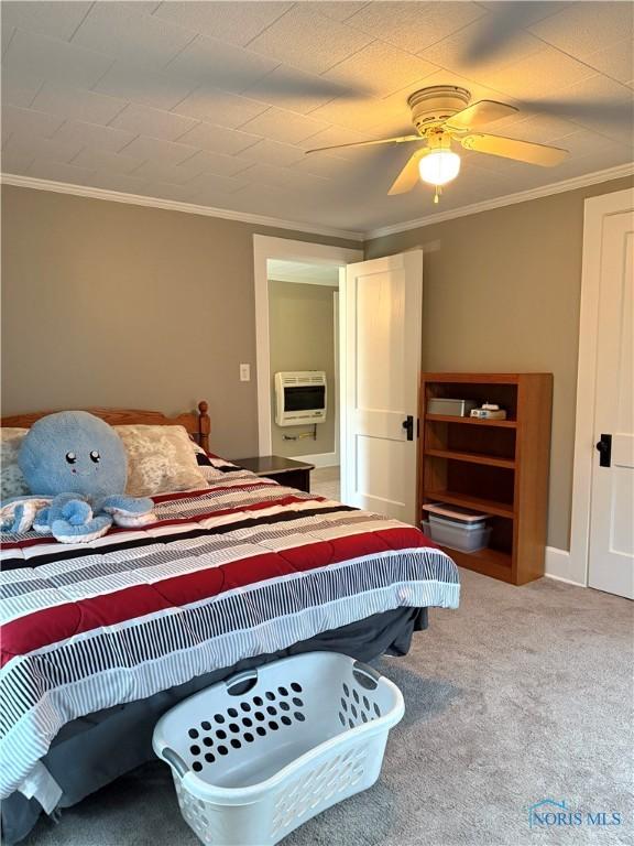 bedroom with heating unit, carpet, ceiling fan, and crown molding