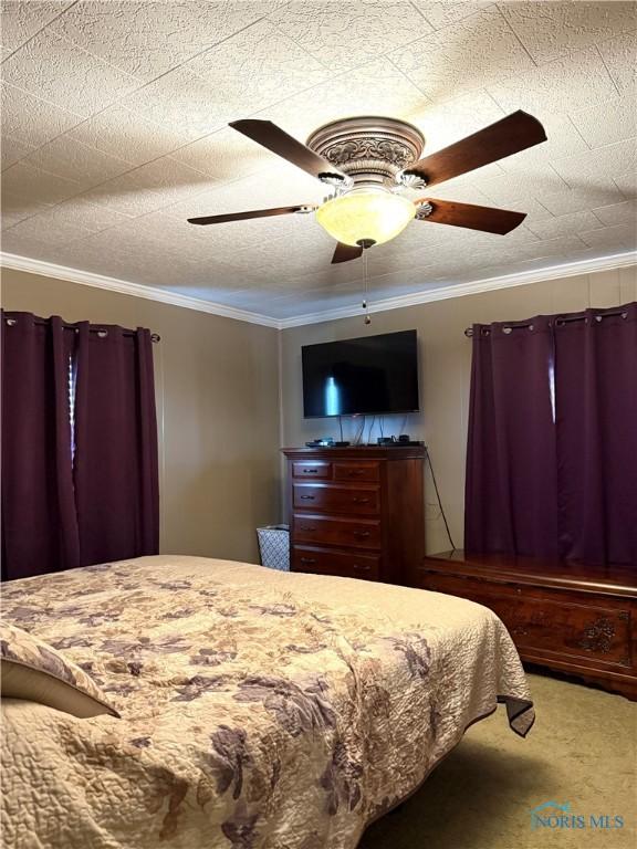 carpeted bedroom featuring a ceiling fan, crown molding, and a textured ceiling