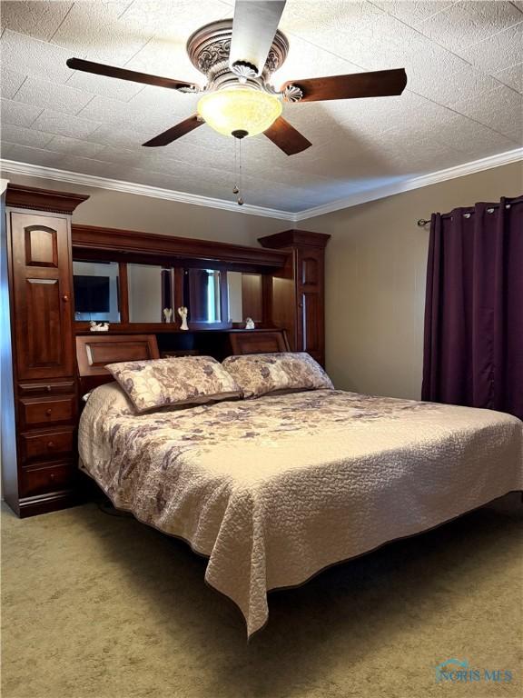 bedroom with ceiling fan, ornamental molding, light colored carpet, and a textured ceiling