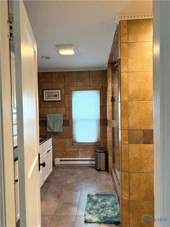 bathroom with tile walls, vanity, a baseboard heating unit, a stall shower, and tile patterned flooring