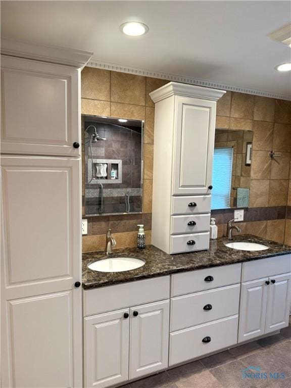 bathroom with double vanity, a sink, a tile shower, and tile walls
