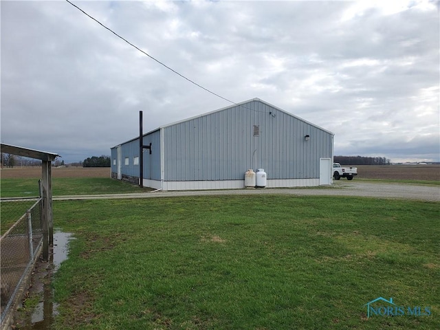 view of pole building featuring fence, driveway, and a yard