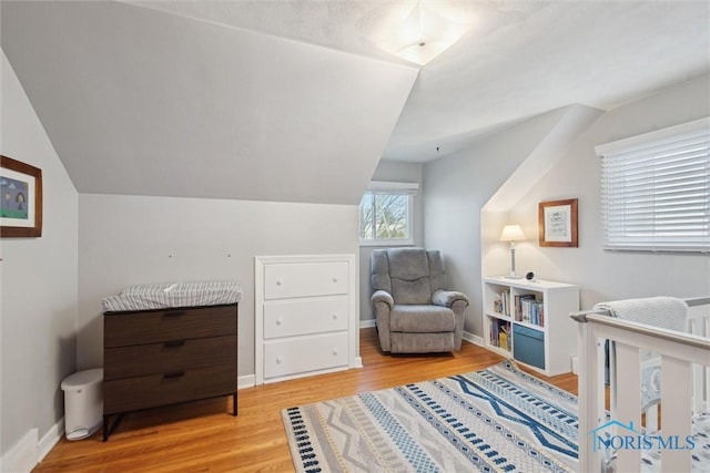 sitting room featuring baseboards, vaulted ceiling, and light wood-style floors