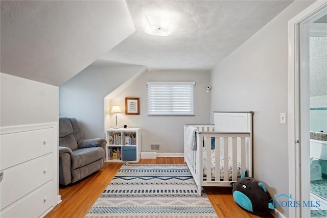 bedroom featuring baseboards, visible vents, vaulted ceiling, and light wood-style floors