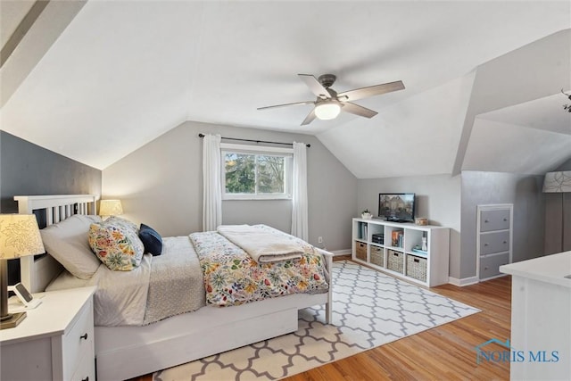 bedroom with baseboards, lofted ceiling, light wood-style flooring, and a ceiling fan