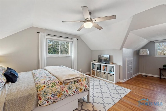 bedroom with baseboards, wood finished floors, vaulted ceiling, and a ceiling fan