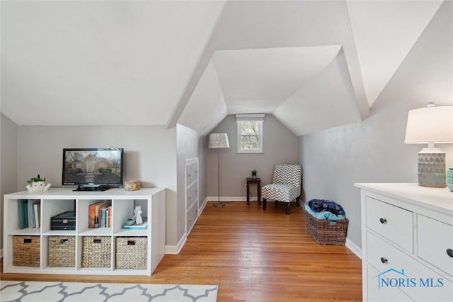 living area with baseboards, lofted ceiling, and light wood-style flooring