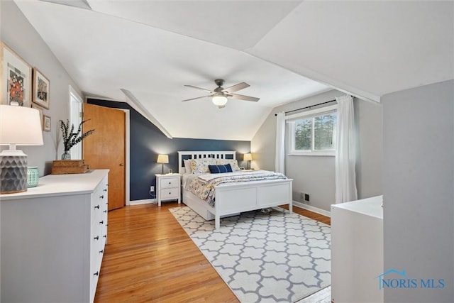 bedroom featuring baseboards, visible vents, vaulted ceiling, and light wood finished floors