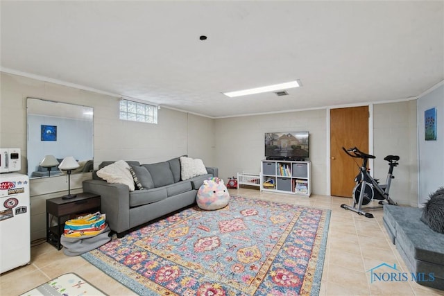 living area with concrete block wall, tile patterned flooring, and ornamental molding