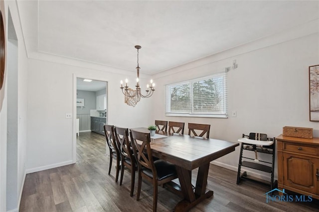 dining area with dark wood finished floors, baseboards, and an inviting chandelier