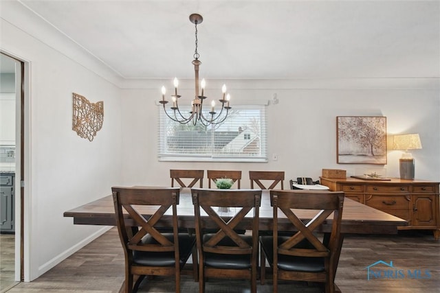 dining space featuring dark wood-style floors, ornamental molding, baseboards, and an inviting chandelier