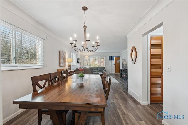 dining space featuring dark wood-style floors, baseboards, and a chandelier