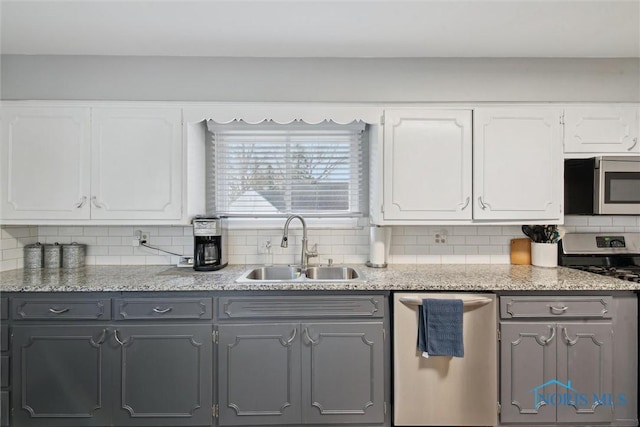 kitchen with a sink, gray cabinets, tasteful backsplash, and appliances with stainless steel finishes