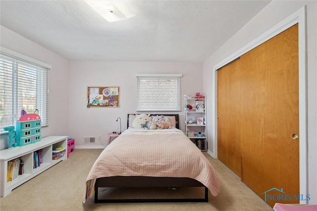 carpeted bedroom featuring a closet, baseboards, and visible vents