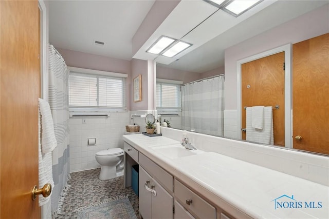 bathroom with tile walls, visible vents, toilet, tile patterned floors, and vanity