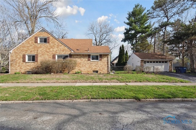 view of side of home featuring fence, a garage, brick siding, an outdoor structure, and a yard