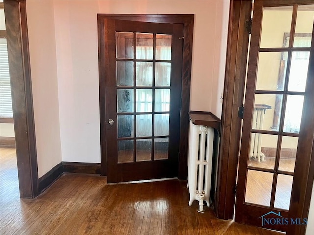 doorway featuring radiator heating unit, hardwood / wood-style floors, and baseboards