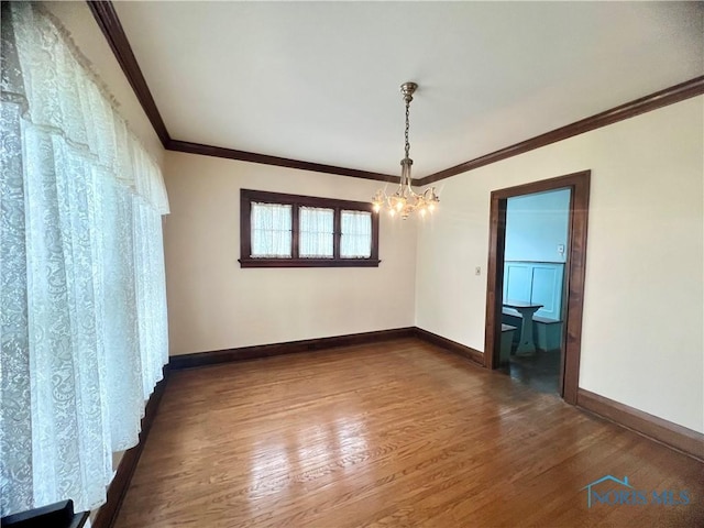 empty room featuring crown molding, baseboards, a notable chandelier, and dark wood-style floors