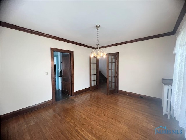 unfurnished room featuring ornamental molding, baseboards, an inviting chandelier, and wood finished floors