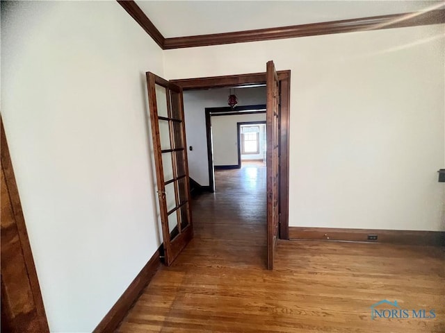 hallway featuring baseboards, crown molding, and wood finished floors
