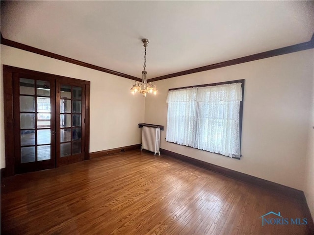 unfurnished dining area featuring crown molding, radiator, an inviting chandelier, wood finished floors, and baseboards