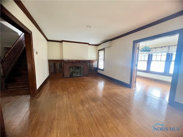 unfurnished living room with ornamental molding, baseboards, wood finished floors, and a wall unit AC