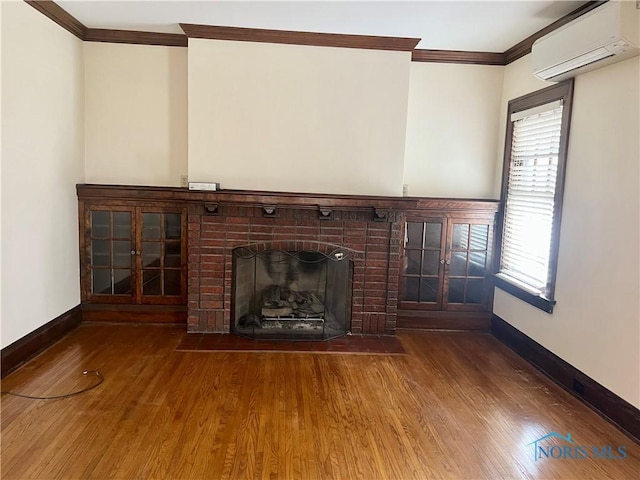 unfurnished living room featuring ornamental molding, baseboards, a wall mounted AC, and wood finished floors
