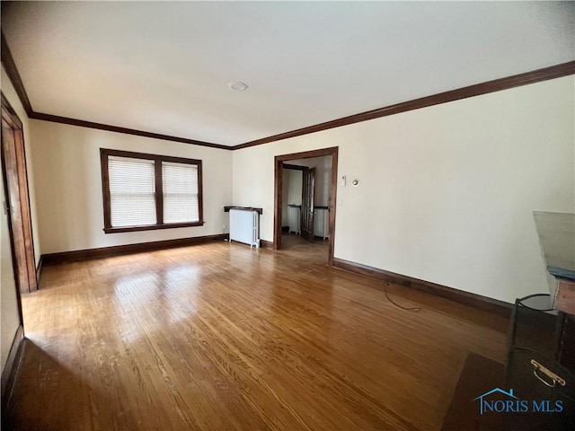 unfurnished living room with baseboards, crown molding, and wood finished floors