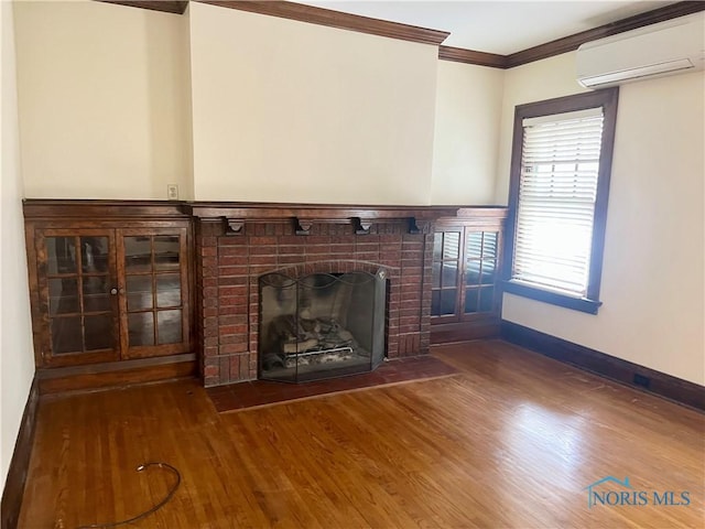 unfurnished living room featuring baseboards, a brick fireplace, a wall mounted air conditioner, crown molding, and wood finished floors
