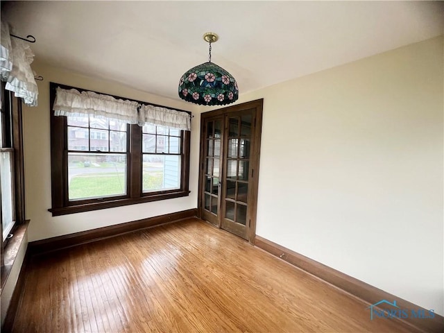 unfurnished dining area featuring hardwood / wood-style floors and baseboards