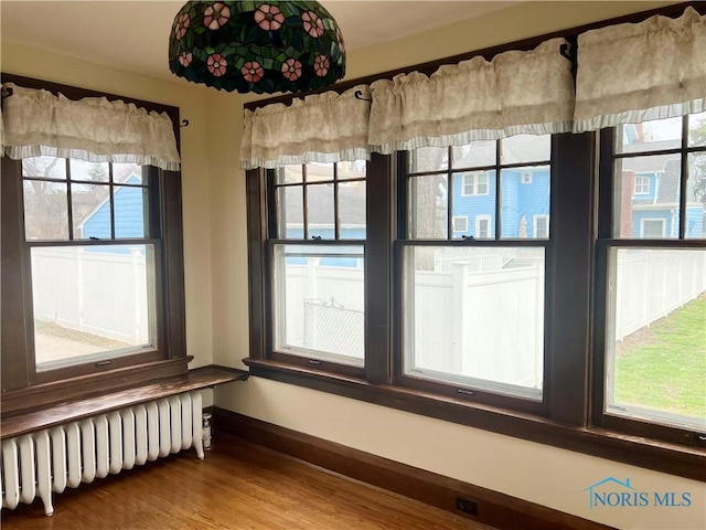empty room with wood finished floors, radiator heating unit, and baseboards