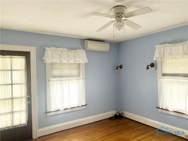 unfurnished room with wood finished floors, ceiling fan, baseboards, and an AC wall unit