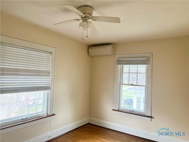 empty room with ceiling fan, baseboards, a wall unit AC, and wood finished floors