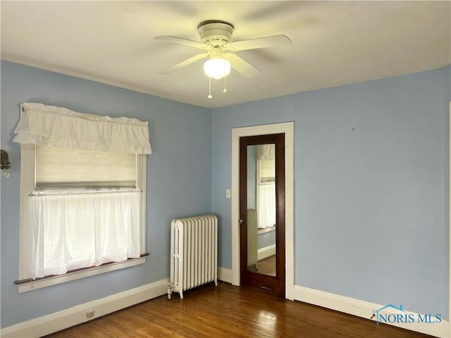 interior space with radiator heating unit, ceiling fan, baseboards, and wood finished floors