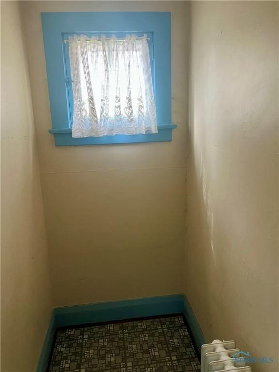 unfurnished room featuring baseboards and radiator