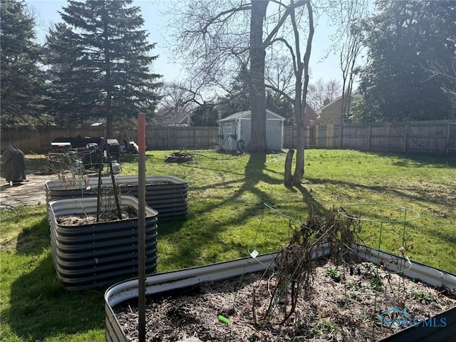view of yard with a fenced backyard, a storage shed, an outbuilding, and a vegetable garden
