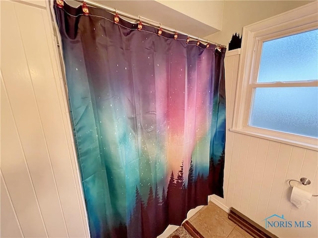 full bathroom featuring a wainscoted wall and curtained shower