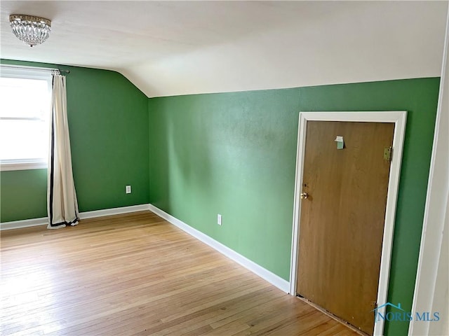 bonus room with light wood-style flooring, baseboards, and lofted ceiling