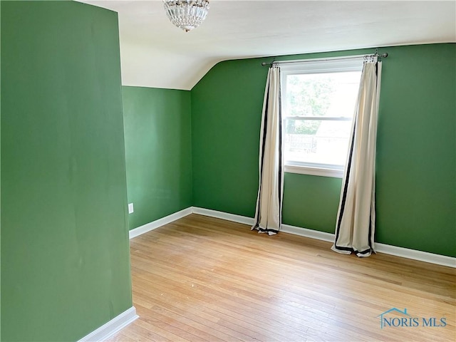 additional living space with vaulted ceiling, baseboards, and hardwood / wood-style floors